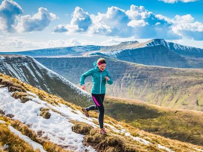 Photo of a women running on a mountain side.